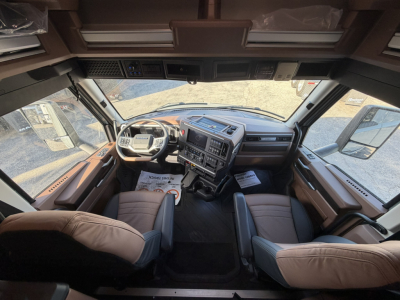 Cab view of a 2026 Mack PR64T76H truck interior showing steering wheel, dashboard, and two captain chairs.