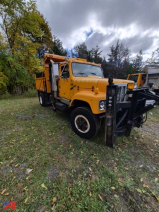 Dump truck with yellow cab in-service showing front snow plow attachment and side utility bed. 2003 International 2574 model, VIN 1HTGEAHR03H561381.