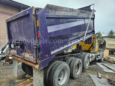 Dump truck bed on a 2014 Mack GU713 with triple rear axle and purple dump bed, stock number 32136-6, VIN 1M2AX04C3EM019013.