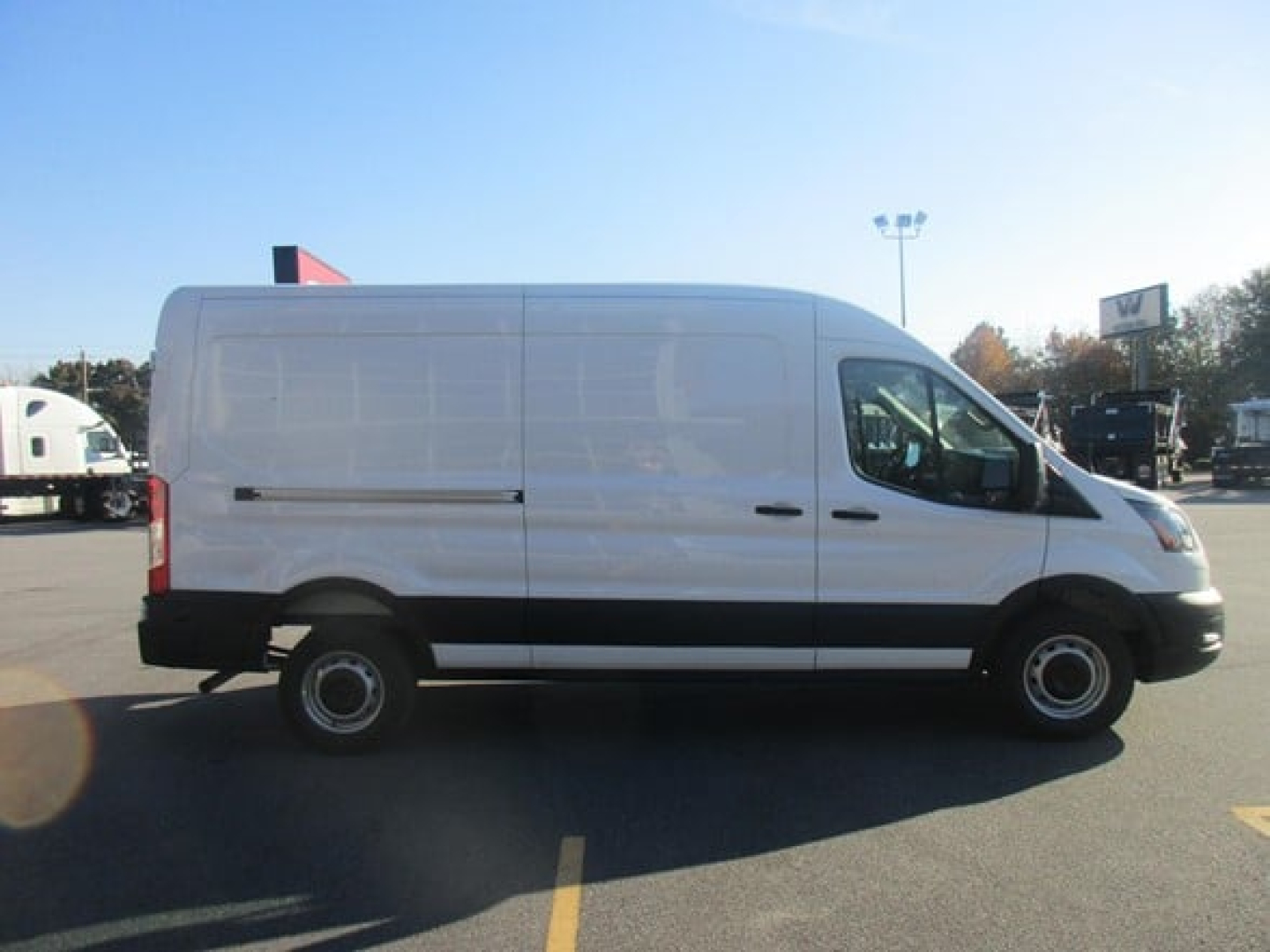 Ford Transit cargo van side view showing blank white exterior with black trim and standard steel wheels.