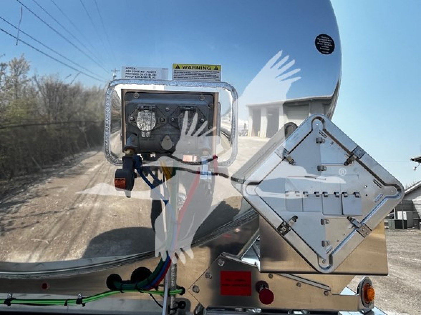 Trailer hitch and connection panel on a Heil 4-Comp trailer showing metal housing, warning sticker, hoses, and a diamond-shaped access cover.