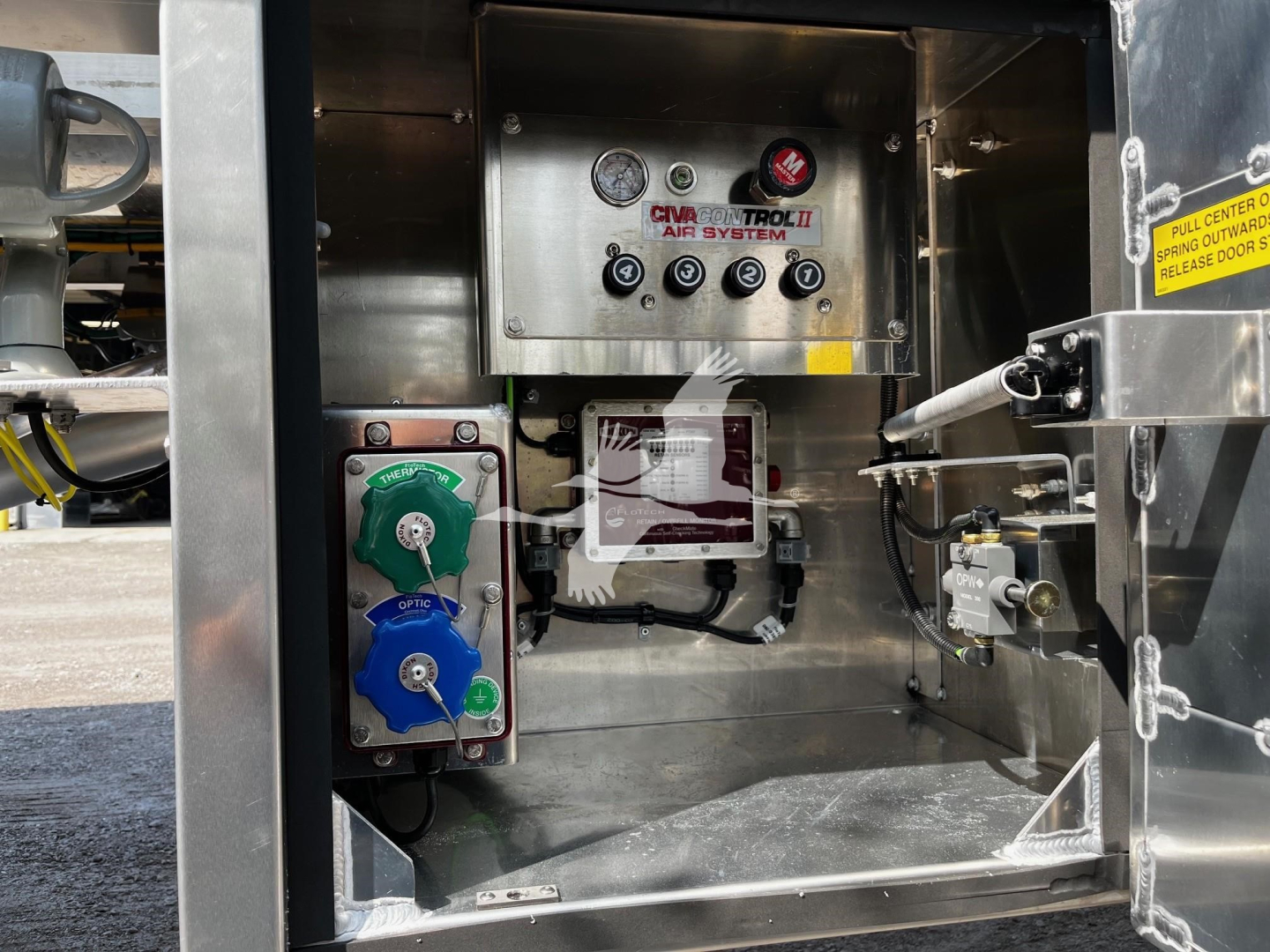 Panel in Heil trailer showing CVA-TROn air system controls, two colored levers (green and blue) for hoses, and gauges with labels. Includes warning sticker and wiring, metallic interior.