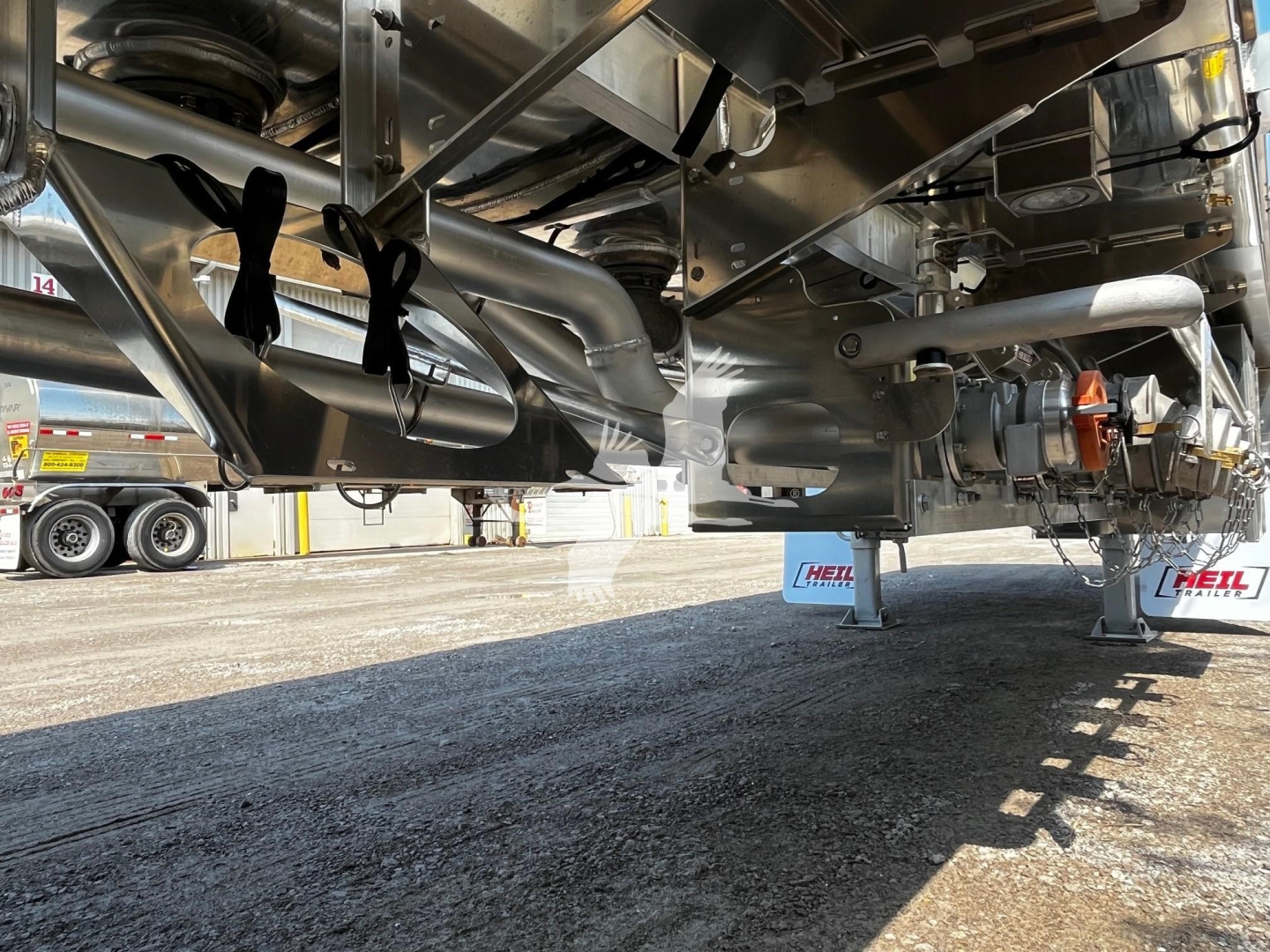 Heil 9500 gallon trailer undercarriage showing dual axles, suspension, piping, and transfer components.