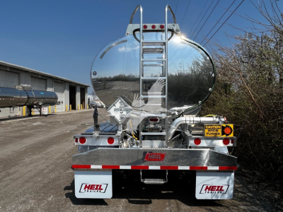 Heli Heil 9500 gal tanker trailer rear view showing polished aluminum tank, ladder, rear bumper, and hazard placards.