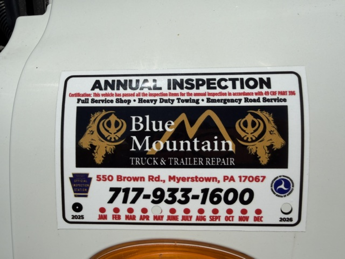 Inspection sticker on a Freightliner Cascadia shows Blue Mountain Truck & Trailer Repair logo with contact number 717-933-1600 and months across the bottom.