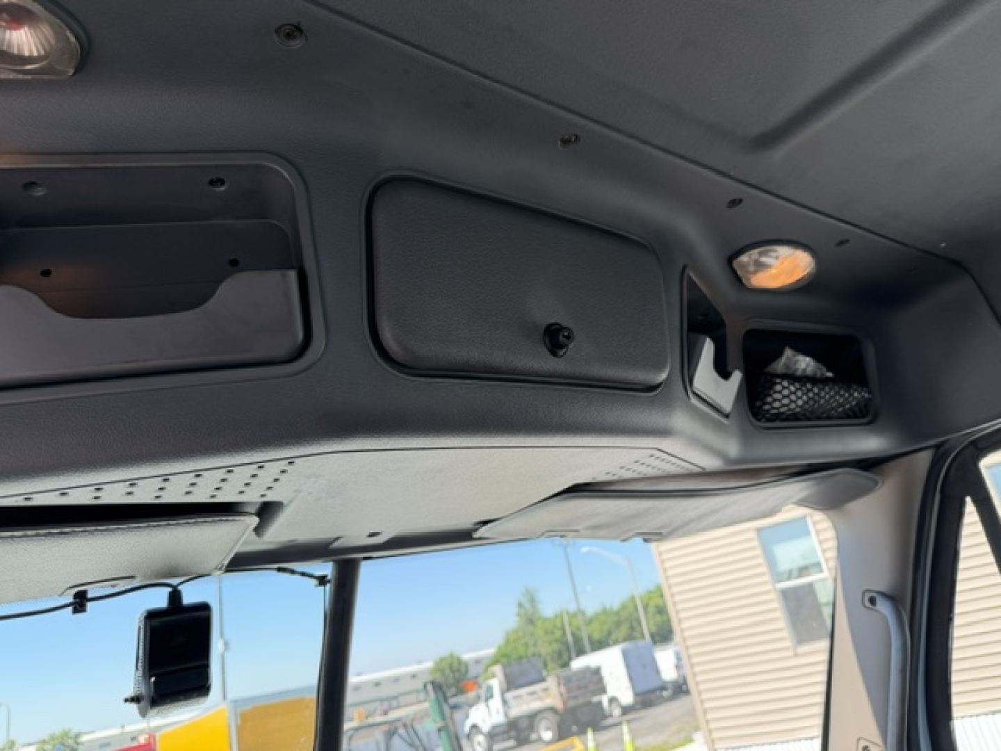 Cab interior of Freightliner Cascadia dashboard area showing overhead panels and interior lights.