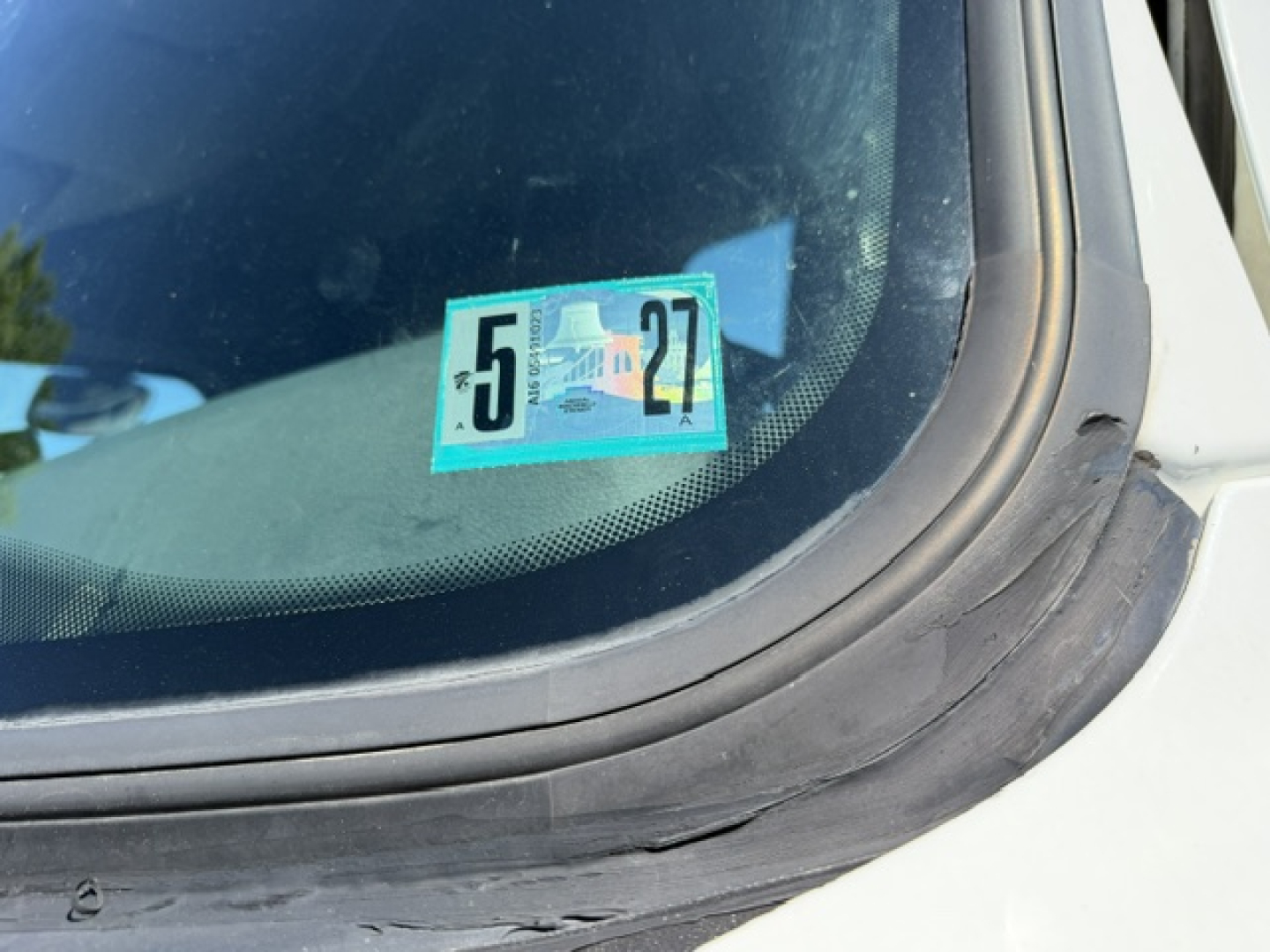 Cab windshield showing state inspection sticker with green background and the numbers 5 and 27 on a Freightliner Cascadia truck