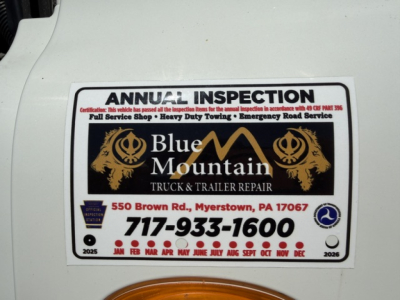 Inspection sticker on a Freightliner Cascadia shows Blue Mountain Truck & Trailer Repair logo with contact number 717-933-1600 and months across the bottom.