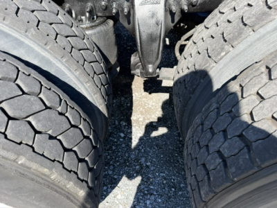 Truck drivetrain view showing tandem rear axles and dual tires of a Freightliner Cascadia CA125DC.