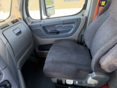Cab interior of a 2014 Freightliner Cascadia CA125DC showing gray fabric driver seat and dashboard edge.