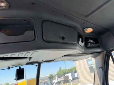 Cab interior of Freightliner Cascadia dashboard area showing overhead panels and interior lights.