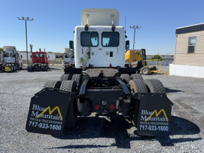 Truck chassis rear view showing dual mudflaps with Blue Mountain logo and contact number.