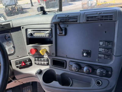 Freightliner Cascadia dash and center console showing instrument cluster, radio, HVAC controls, and electrical switches.