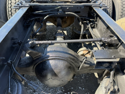 Rear underside of a Freightliner Cascadia drive axle and suspension showing differential housing and driveshaft with chassis rails.
