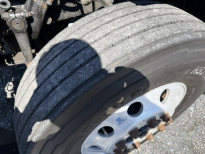 Truck wheel and dual rear axle area showing large tire with white rim and lug nuts.