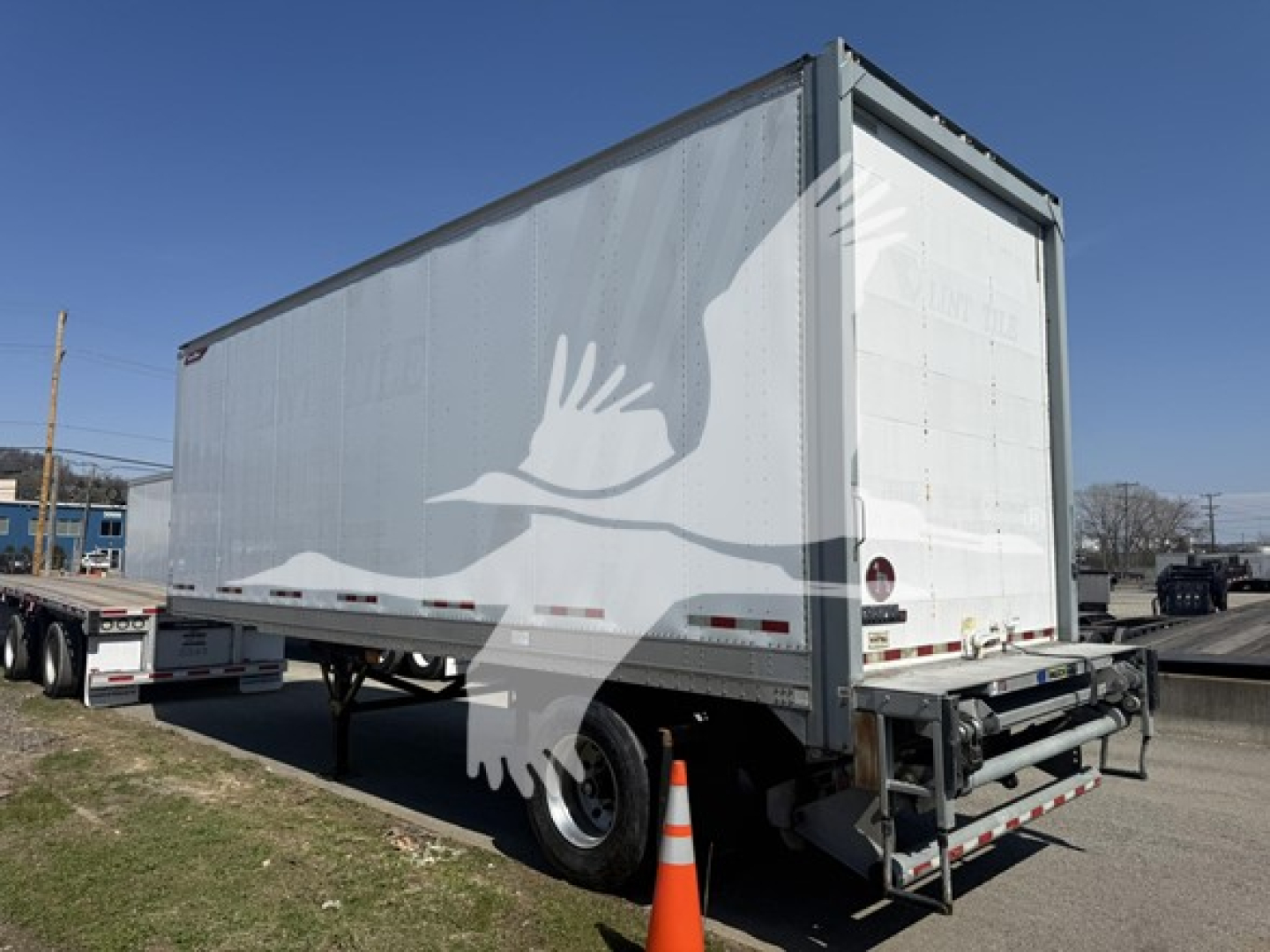 Trailer side and rear view showing a white Great Dane Pup trailer with ramp, reflective strips, and rear bumper; VIN tag and stock number not visible