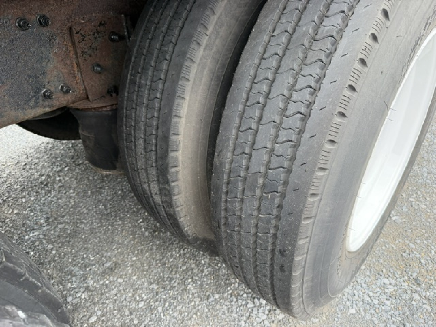 Volvo VHD truck wheel and dual tires showing tread and suspension area with rusted chassis.