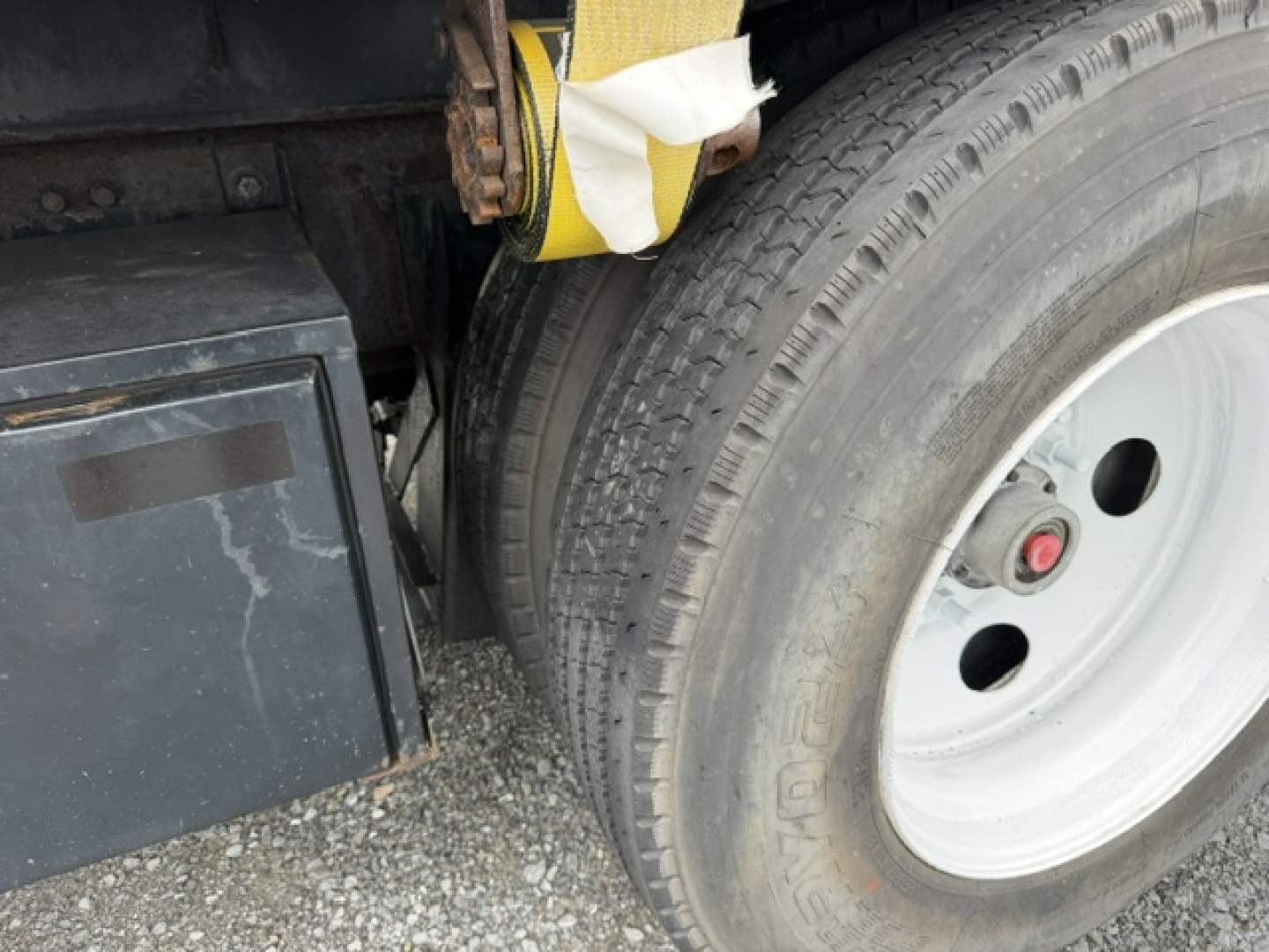 Volvo VHD truck wheel and fender area showing front tire and wheel with valve cap, part of flatbed chassis.