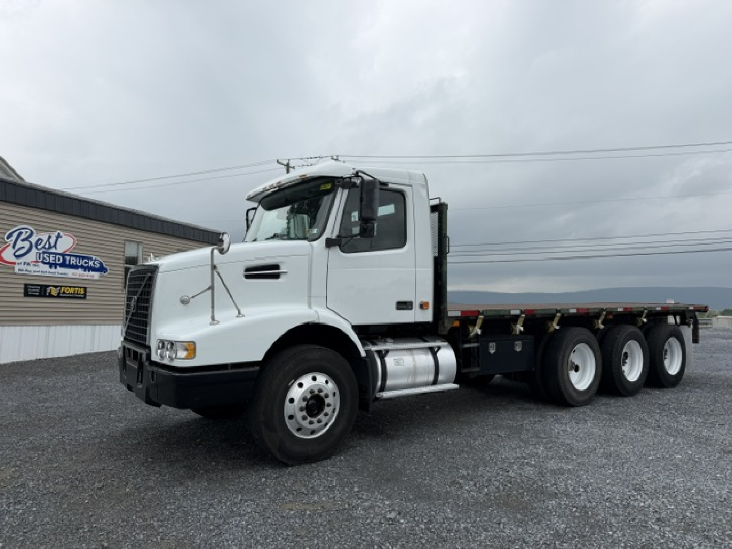 Volvo VHD truck in service bay shows white cab and multi-axle flatbed configuration.