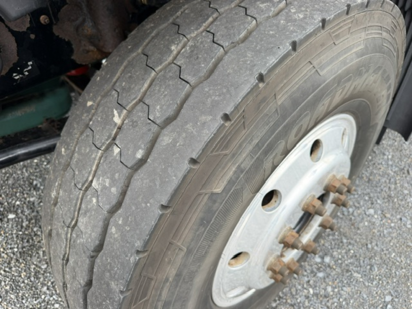Volvo truck wheel and tire close-up showing front dual-wheel hub with rusted lug nuts and rugged tread.