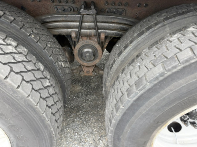 View of the underside between dual rear axles showing suspension, leaf springs, and tires.