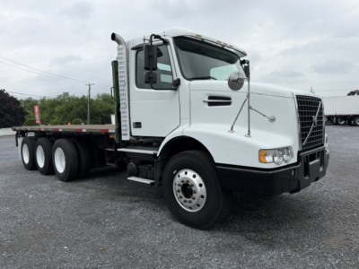  Volvo VHD truck cab and flatbed seen from front-left angle showing white cab, dual rear axles, and trailer bed. Visible text: no legible labels.
