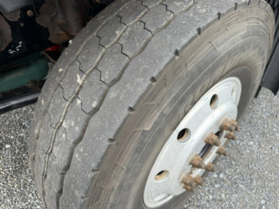 Volvo truck wheel and tire close-up showing front dual-wheel hub with rusted lug nuts and rugged tread.