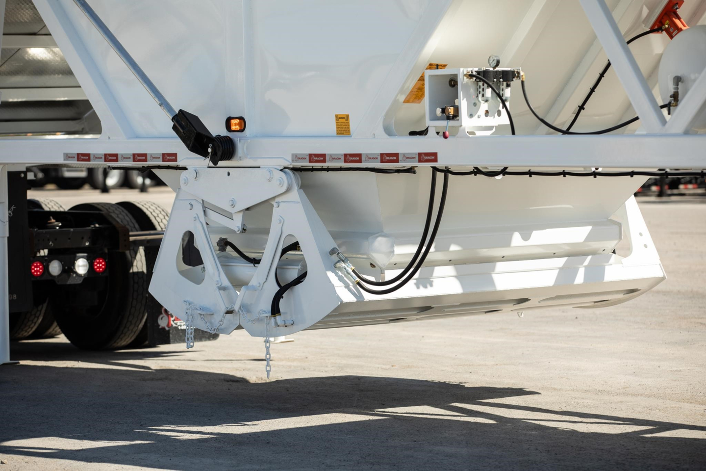 Dump trailer rear view showing suspension and hydraulic lines on a white Ranco wet sand switchgate bottom dump.