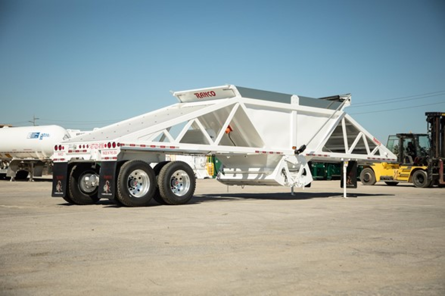 Ranco Wet Sand Switchgate Bottom Dump trailer with tri-axle rear and white frame, showing brand name RANCO on the upper beam.
