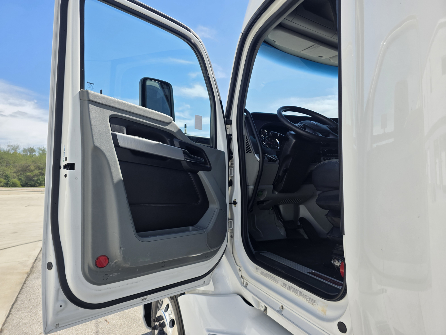 Kenworth T680 cab interior door open showing steering wheel and seat area