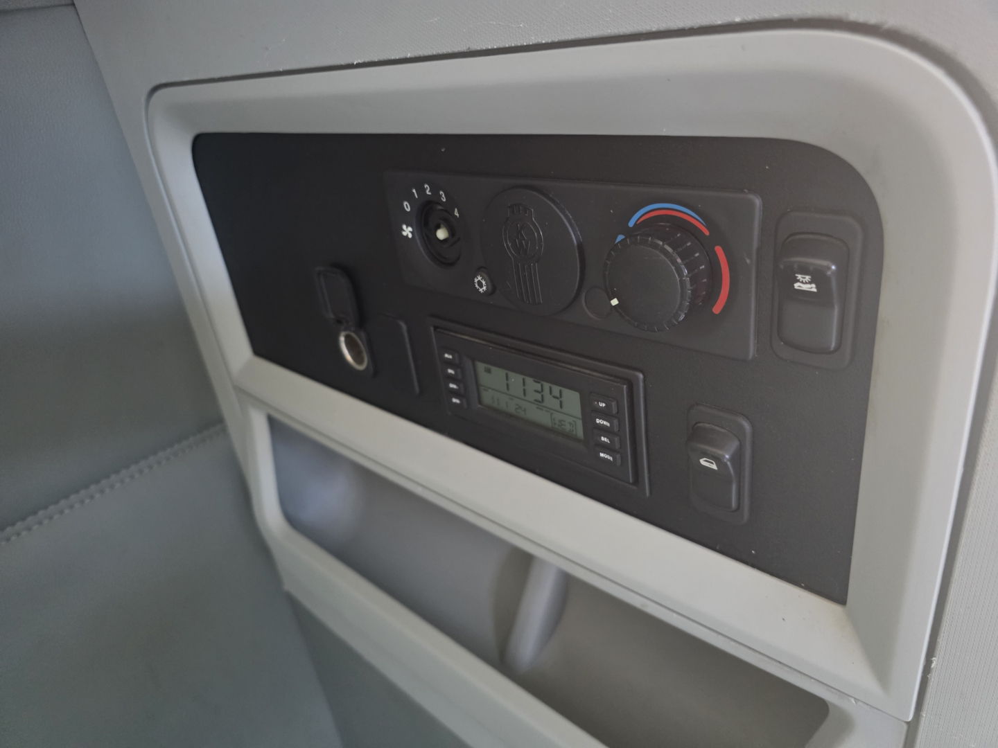 Truck cab climate control panel with circular knobs and digital display showing 1134. Left ignition slot and small lever visible.