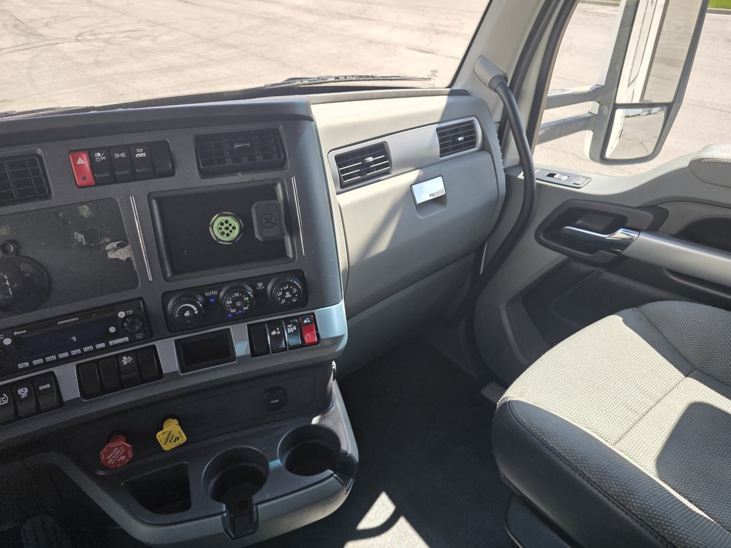 Kenworth T680 truck cockpit interior showing dashboard controls and cup holders.