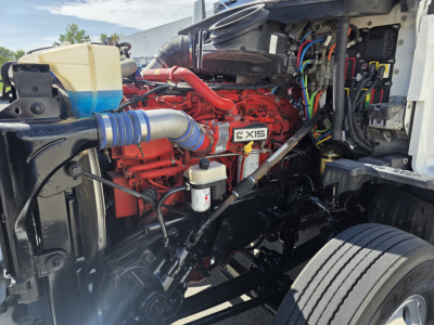 Kenworth T680 engine bay showing XD-15 diesel engine with red components, blue intercooler hose, coolant reservoir, and various wiring harnesses.