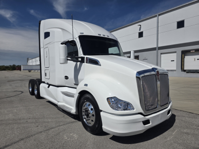 Kenworth T680 tractor-trailer cab, white, front three-quarter view, showing grille, headlights, and side mirror.
