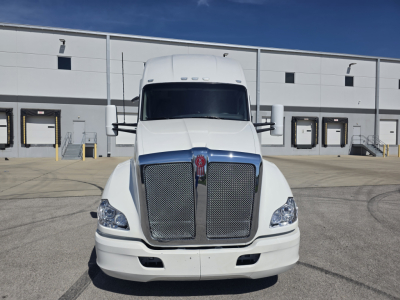Kenworth T680 front view showing large chrome grille and headlights in a loading area.