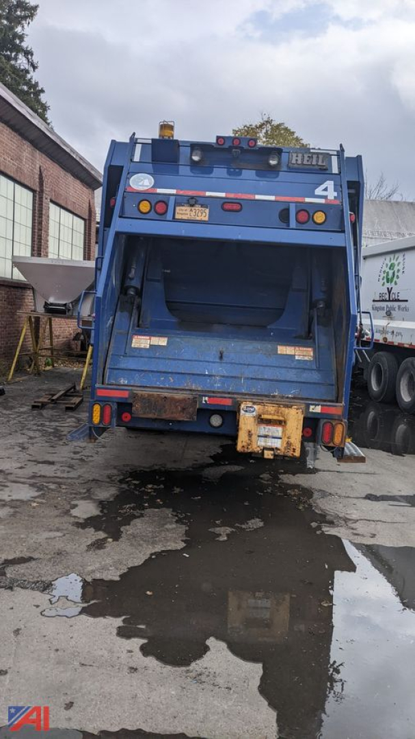 Rear view of a blue 2013 Mack LEU 613 trash truck showing rear hopper and taillights.
