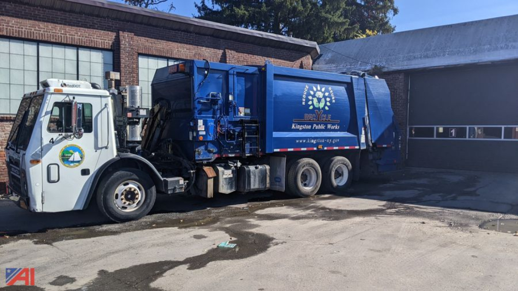 Rear loader garbage truck in service showing blue refuse body and Mack LEU 613 chassis with white cab.
