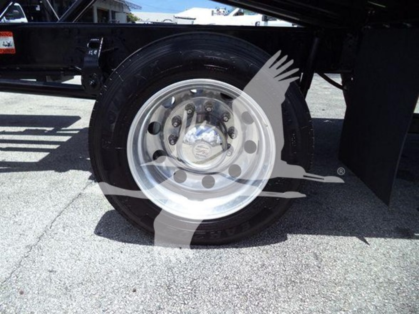 Truck wheel and front suspension of a 2020 Hino 268A rollback truck showing a silver alloy wheel and black tire.
