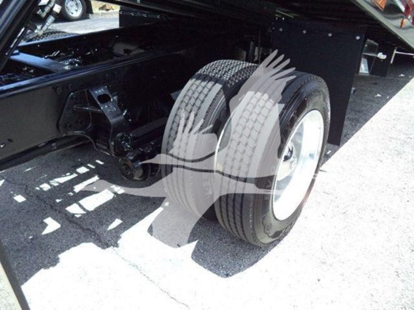 Trailer tow truck chassis showing dual rear wheels and part of the frame; visible tires and axle components under a Hino 268A rollback truck.