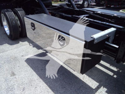 Truck tool box mounted on chassis with reflective surface and storage lid; no visible branding text readable.