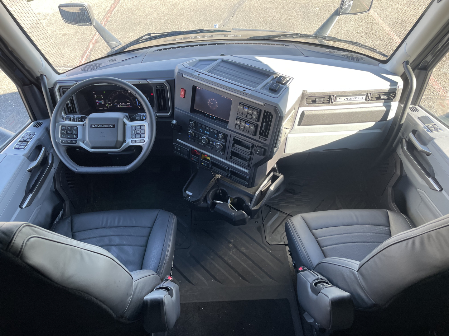 Cab interior of a 2026 Mack PR64T76H showing steering wheel, dashboard with multi-function display, center console, and two front seats.