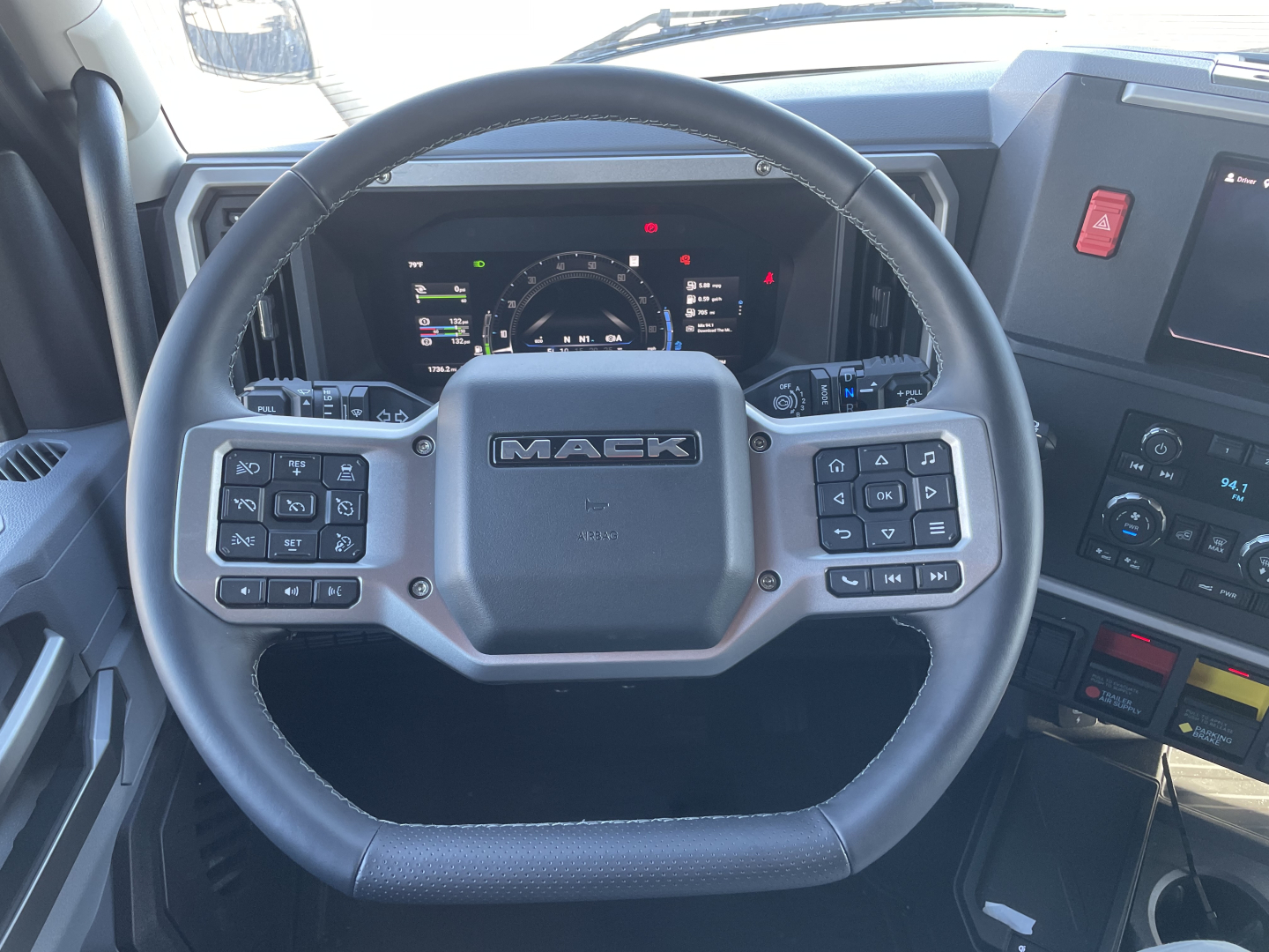 Steering wheel in Mack PR64T76H truck cab with dashboard controls and digital gauge cluster; visible text includes MACK on the steering wheel center.