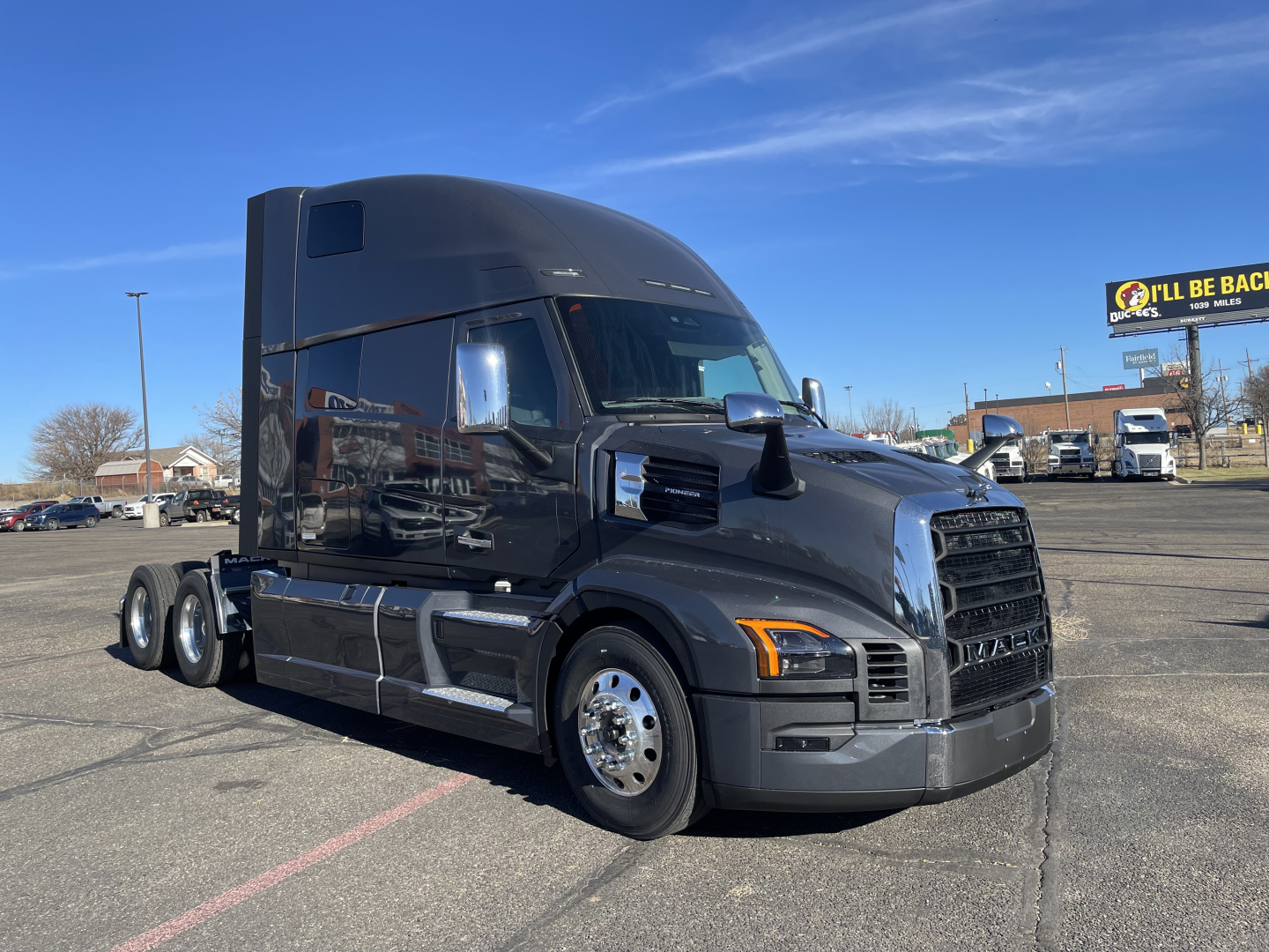 Black Mack PR64T76H tractor truck in a parking lot, side view, cab with high roof, chrome mirrors, chrome wheels, grille.