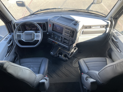 Cab interior of a 2026 Mack PR64T76H showing steering wheel, dashboard with multi-function display, center console, and two front seats.