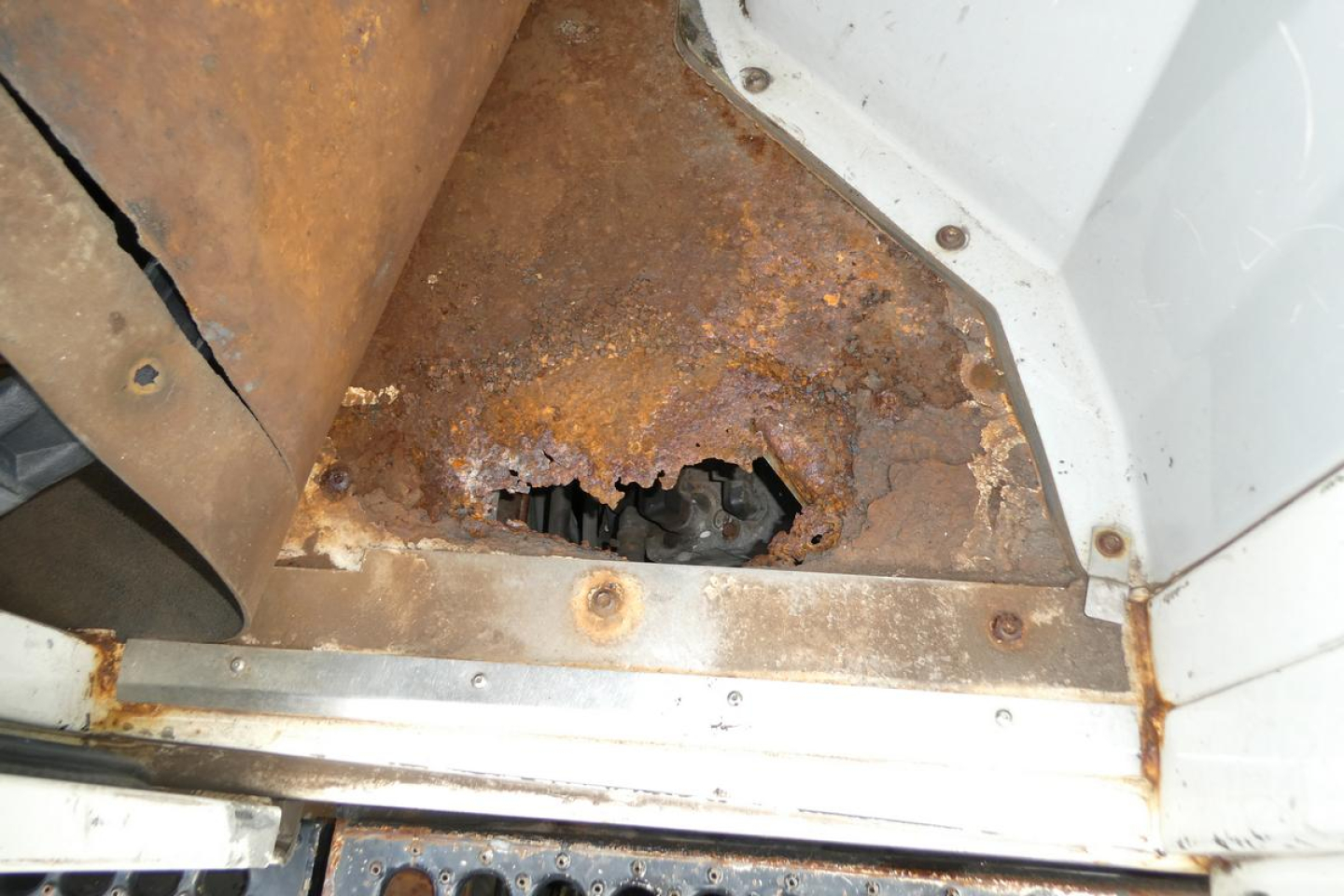 Truck undercarriage showing rust damage to floor and side panel near door jamb on a 2007 Ottawa 4x2 in-yard vehicle.