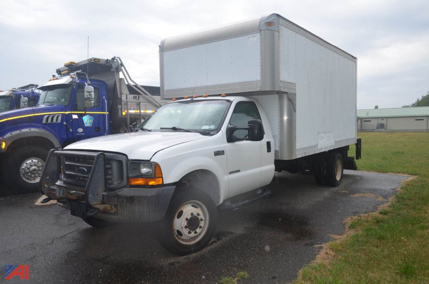 Box truck showing white Ford F-450 Super Duty box body with dual rear wheels and black front grille; overcast lot setting.