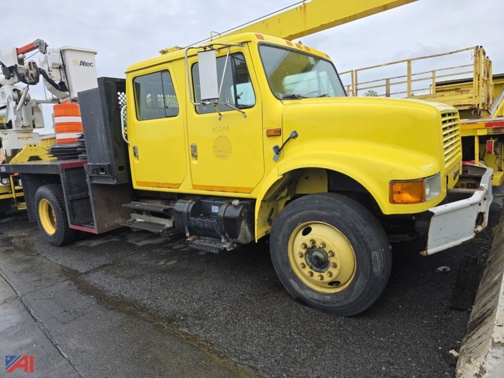 International 4700 flatbed truck in-service shown side view with yellow cab and flatbed equipment.