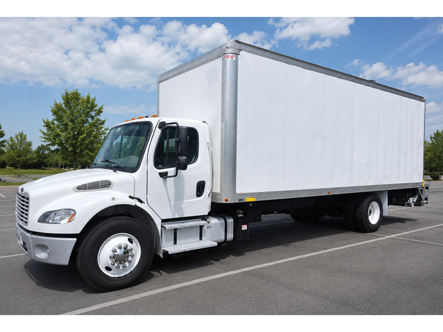 Freightliner M2 106 box truck side view showing white cab and large box cargo area