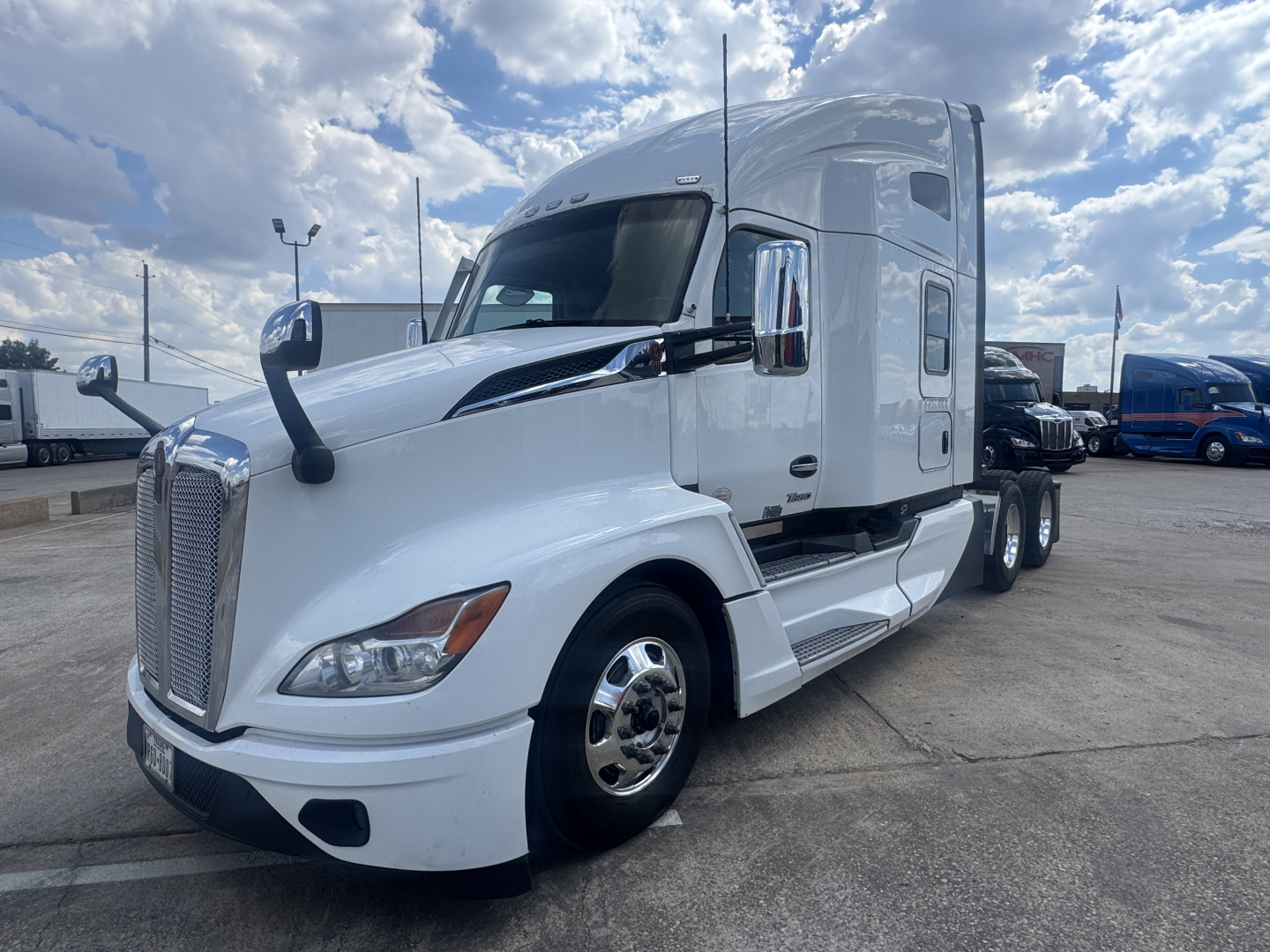 Kenworth T680 conventional sleeper truck in white, front-left view showing cab and wheel, with chrome mirrors and engine hood.