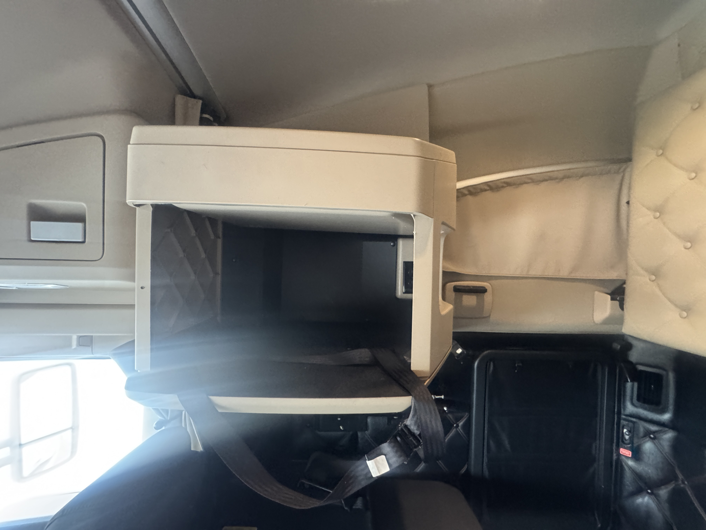 Kenworth T680 sleeper cab interior with open storage compartment and dashboard area visible.